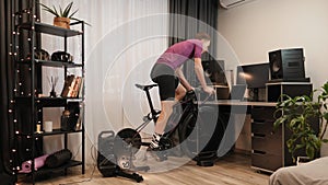 Indoor cycling. Cycling at home. Male sportsman is training on stationary exercise bike at home. Cyclist is spinning pedals on sma