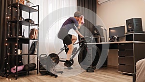 Indoor cycling on stationary bicycle. Woman is training on smart bike trainer at home. Female cyclist is doing cardio fitness work