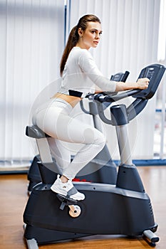 Indoor cycling woman doing cardio workout biking on indoors gym bike.