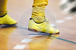 Indoor football player with classic ball. Futsal training for children. Legs of young futsal player in soccer cleats and socks