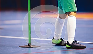 Indoor football player and training pole. Futsal training for children. Legs of young futsal player in soccer cleats and socks