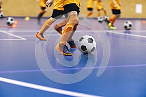 Indoor football training for youth team. Young boys with soccer balls running on wooden parquet