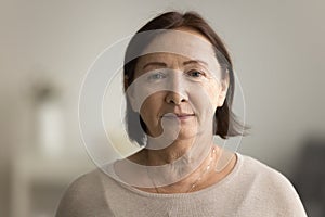 Indoor head shot portrait of serious positive old mature woman