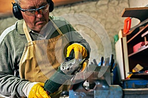 Indoor image of adult worker man manufacturing in his workshop. Carpenter male grinding with sparks in repair shop