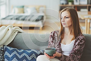 indoor lifestyle portrait of young woman relaxing at home with cup of hot tea or coffee