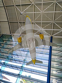 an indoor miniature white and yellow plane hanging from the ceiling of an airport demonstration the aeronautic technology where