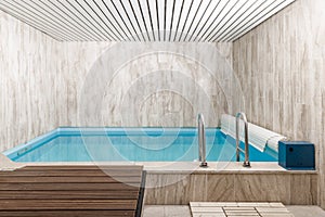 Indoor modern small swimming pool in light grey sauna interior