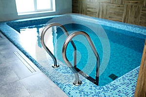Indoor modern swimming pool in hotel spa center. The sauna finished with a light tree and pool, the laid out blue tile