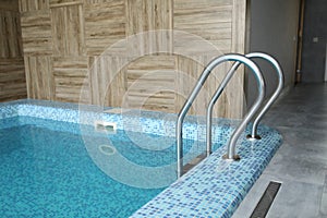 Indoor modern swimming pool in hotel spa center. The sauna finished with a light tree and pool, the laid out blue tile