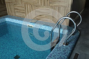 Indoor modern swimming pool in hotel spa center. The sauna finished with a light tree and pool, the laid out blue tile