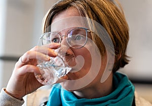 Indoor portrait of a 35 year old woman drinking a glass of water