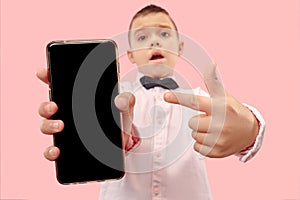 Indoor portrait of attractive young boy holding blank smartphone