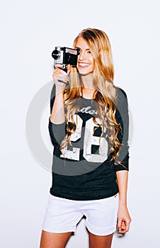 Indoor Portrait of beautiful blonde young woman holding vintage 8mm camera. Warm color.