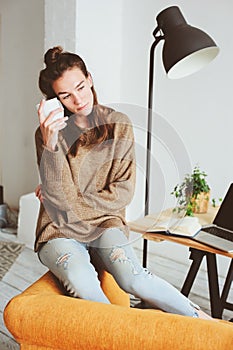 Indoor portrait of beautiful feminine thoughtful young women alone in the room with cup of tea or coffee