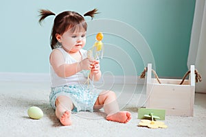 Indoor portrait of cute happy baby girl playing with easter decorations