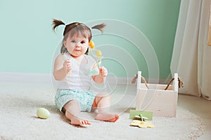 Indoor portrait of cute happy baby girl playing with easter decorations