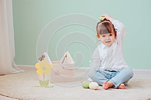 Indoor portrait of cute happy baby girl playing with easter decorations