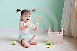 Indoor portrait of cute happy baby girl playing with easter decorations