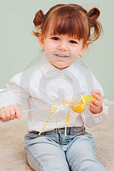 Indoor portrait of cute happy baby girl playing with easter decorations