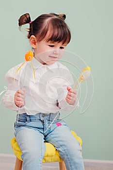 Indoor portrait of cute happy baby girl playing with easter decorations