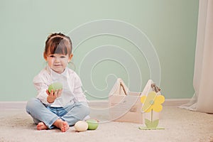 Indoor portrait of cute happy baby girl playing with easter decorations