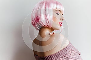 Indoor portrait of graceful white woman posing with pleasure in studio. Photo of lovely girl in pink peruke dreaming