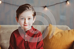 indoor portrait of happy handsome stylish child boy sitting on cozy couch