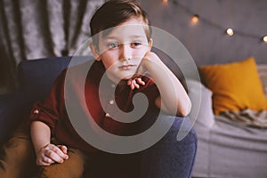 Indoor portrait of happy handsome stylish child boy sitting on cozy couch