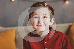 indoor portrait of happy handsome stylish child boy sitting on cozy couch