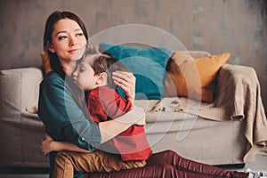 indoor portrait of happy loving mother comforting toddler son at home.