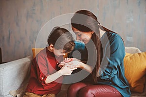 Indoor portrait of happy mother and child son sitting on couch and playing