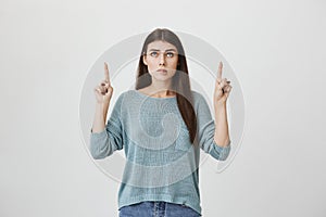 Indoor portrait of hot caucasian woman with long hair, pointing and looking up, expressing desire by biting lips