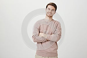 Indoor portrait of positive confident young businessman standing with crossed hands and adorable smile, being satisfied