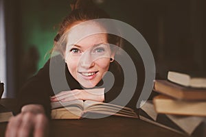 indoor portrait of redhead happy student woman learning or reading books