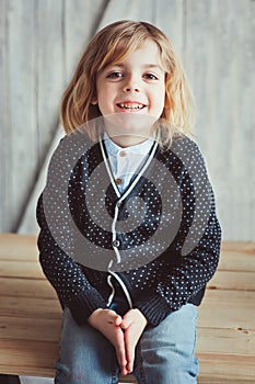 Indoor portrait of 5 years old boy with long hair sitting on table