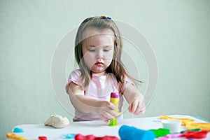 Indoor portrait of young 2 years happy smiling caucasian child girl playing with play dough