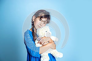 Indoor portrait of young child girl with teddy bear, studio shot