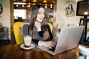 Indoor portrait of a young girl she works as a freelancer in a cafe drinking a delicious hot Cup of coffee from text send mail loa