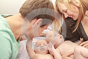 indoor portrait of young happy smiling mother and father with twin babies at home