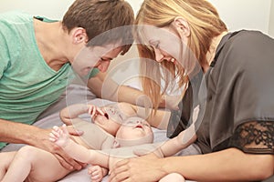 indoor portrait of young happy smiling mother and father with twin babies at home