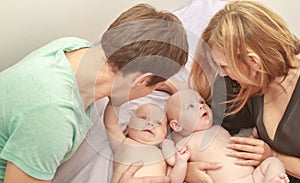 indoor portrait of young happy smiling mother and father with twin babies at home