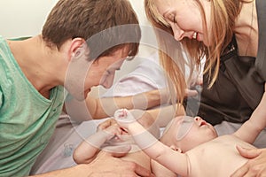 indoor portrait of young happy smiling mother and father with twin babies at home