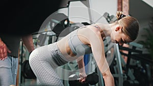 Indoor shot of a beautiful caucasian brunette girl and her personal trainer. Woman is being thought how to lean on a