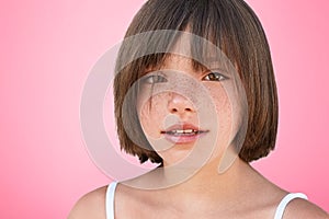 Indoor shot of confident freckled beautiful small female child with bobbed hairstyle looks at camera, glad to be photographed in s