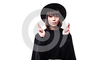 Indoor shot of glad happy woman smiles broadly, keeps fingers crossed, hopes for good luck, isolated against white background with