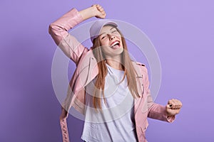 Indoor shot of happy excited woman clenching her fists, screaming happily, celebrating her success, having positive emotions,