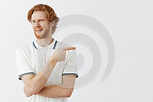 Indoor shot of picky displeased and dissatisfied handsome redhead male employee in white polo shirt frowning turning