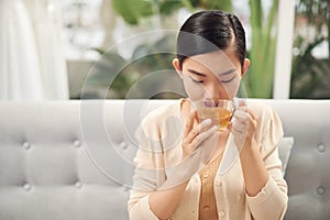 Indoor shot of a smiling asian woman drinking tea