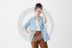 Indoor shot of unhappy young woman suffering from bad headache or migraine after hard working day, having stressed