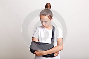 Indoor shot of woman with bun hairstyle with broken arm in splint suffers from hand injury, insurance and health care, girl